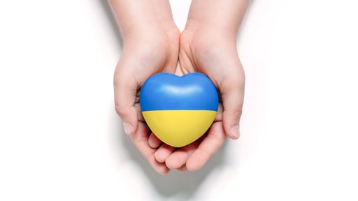 Web_Desktop-High angle view of child hands holding ukraine flag painted heart isolated on white background