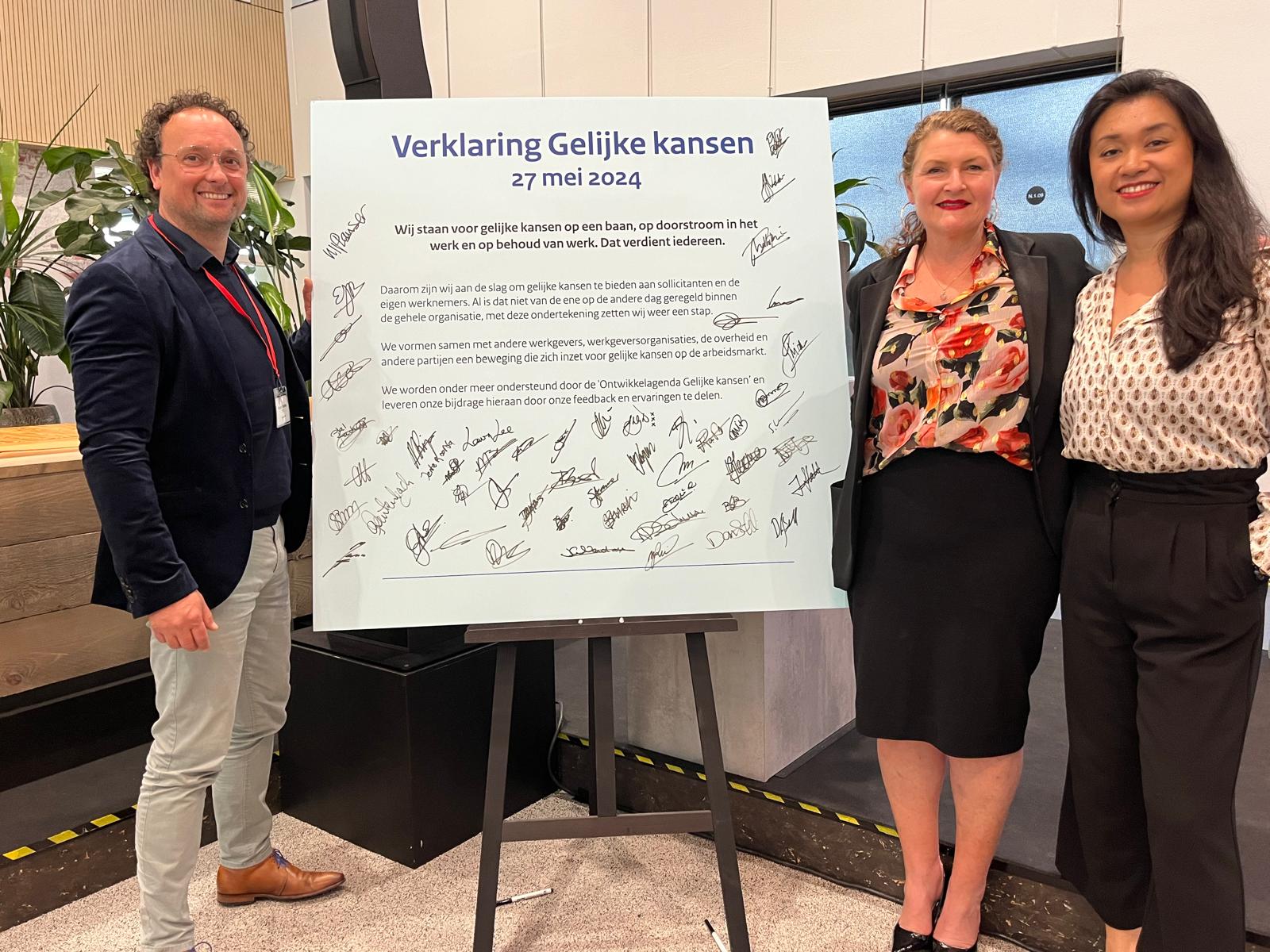 De Verklaring Gelijke kansen met alle handtekening. Links van het bord Robert Oosting, Head Of Diversity & Inclusion en rechts van de verklaring Gemmie Hermens, People & Culture director, en Hanni Wongsosumarto, Projectmanager Diversity & Inclusion