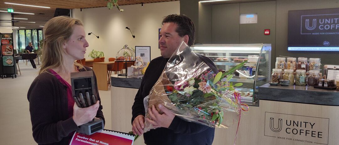 Marc Nieuwmeijer neemt de bokaal voor de 'Best at Work Award 2024 in ontvangst van Sabine van Hoon van Yougov bij de Unity Coffee Bar van ISS